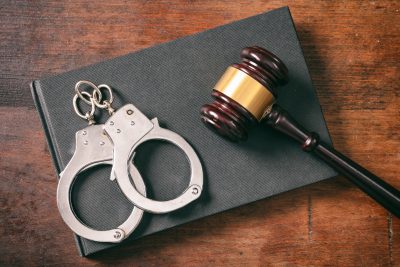 Handcuffs, gavel on book on a wooden background.
