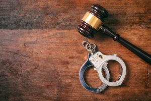 Handcuffs isolated and a gavel with copy space on a wooden background.