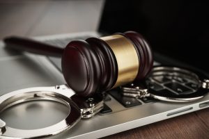 handcuffs and judge gavel on computer cyber crime concept